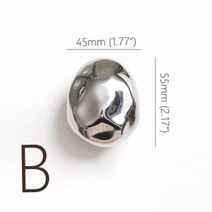 May include: A white ceramic mug with a black handle and the text "But First, Coffee" in a black, handwritten-style font. The mug is on a white surface.