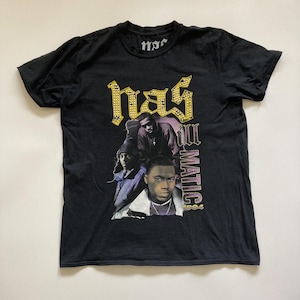 May include: Black t-shirt featuring a graphic of Nas, with the text "Nas Illmatic 1994". The word "nas" is in a gold, jeweled font. The shirt has a crew neck and short sleeves.