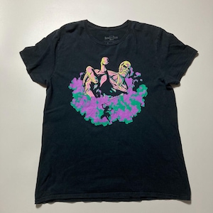 Puede incluir: Camiseta negra con un gráfico colorido de una figura musculosa con un rostro detallado, emergiendo de una nube de humo morado y verde. La camiseta tiene cuello redondo y mangas cortas. El texto "Attack on Titan" es visible.