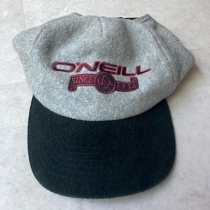 May include: A gray and black O'Neill baseball cap. The cap features the text "O'NEILL SINCE USA 1952" embroidered in red. The top of the cap is gray, and the bill is black.