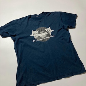 以下が含まれることがあります： ネイビーブルーのTシャツ。レコードのデザインの中に2つの顔が描かれたグラフィックデザインが特徴です。「DJ Format & Abdominal」の文字が下にプリントされています。柔らかい素材で作られています。