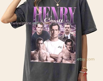 May include: Dark gray t-shirt featuring a collage of images of Henry Cavill, with the name "HENRY Cavill" in a purple and white design. The shirt has a vintage aesthetic, with the Etsy shop name "twivestore.etsy.com" printed on it.