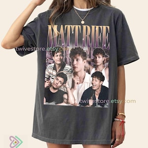 Puede incluir: Camiseta gris oscuro con un collage de imágenes de Matt Rife, y el nombre "MATT RIFE" en una fuente degradada dorada y morada. El nombre de la tienda de Etsy "twivestore.etsy.com" está impreso en la camiseta.