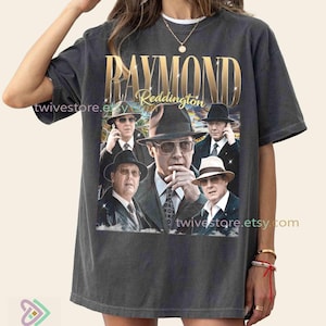 Puede incluir: Camiseta gris oscuro con un diseño gráfico de Raymond Reddington y el texto "Raymond Reddington" en letras doradas. La imagen incluye múltiples retratos del personaje. El nombre de la tienda Etsy es visible.