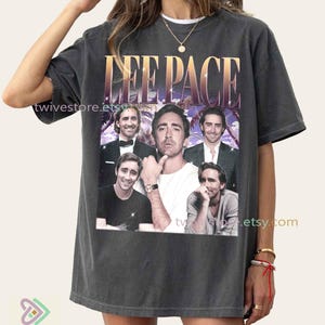 Könnte beinhalten: Dunkelgraues T-Shirt mit einer Collage von Bildern von Lee Pace und dem Text "LEE PACE" in einem Gold- und Lila-Farbverlauf. Das Shirt hat einen Vintage-Look.