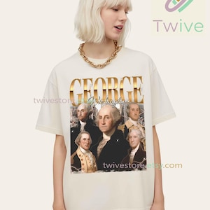 May include: Cream-colored t-shirt featuring a graphic of George Washington with the word "GEORGE" in gold lettering. The shirt also includes the text "Washington" and the Etsy shop's URL.