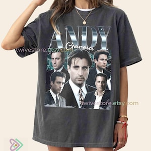 Puede incluir: Camiseta gris oscuro con un collage de imágenes de Andy García y el nombre "ANDY Garcia" en una fuente plateada reflectante. La camiseta tiene un aspecto vintage y desgastado, con el nombre de la tienda Etsy "twivestore.etsy.com" impreso.
