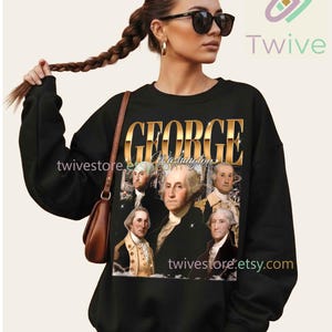 May include: Black sweatshirt featuring a graphic of George Washington and the text "GEORGE Washington" in gold lettering. The sweatshirt has long sleeves and a crew neck. The Etsy shop name "twivestore.etsy.com" is also visible.