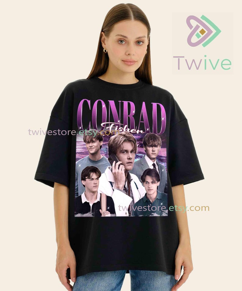 May include: Black t-shirt featuring a collage of images of a person, with the name "CONRAD Fisher" in a purple and white design. The shirt has a crew neck and short sleeves. The Twive logo is in the upper right corner.