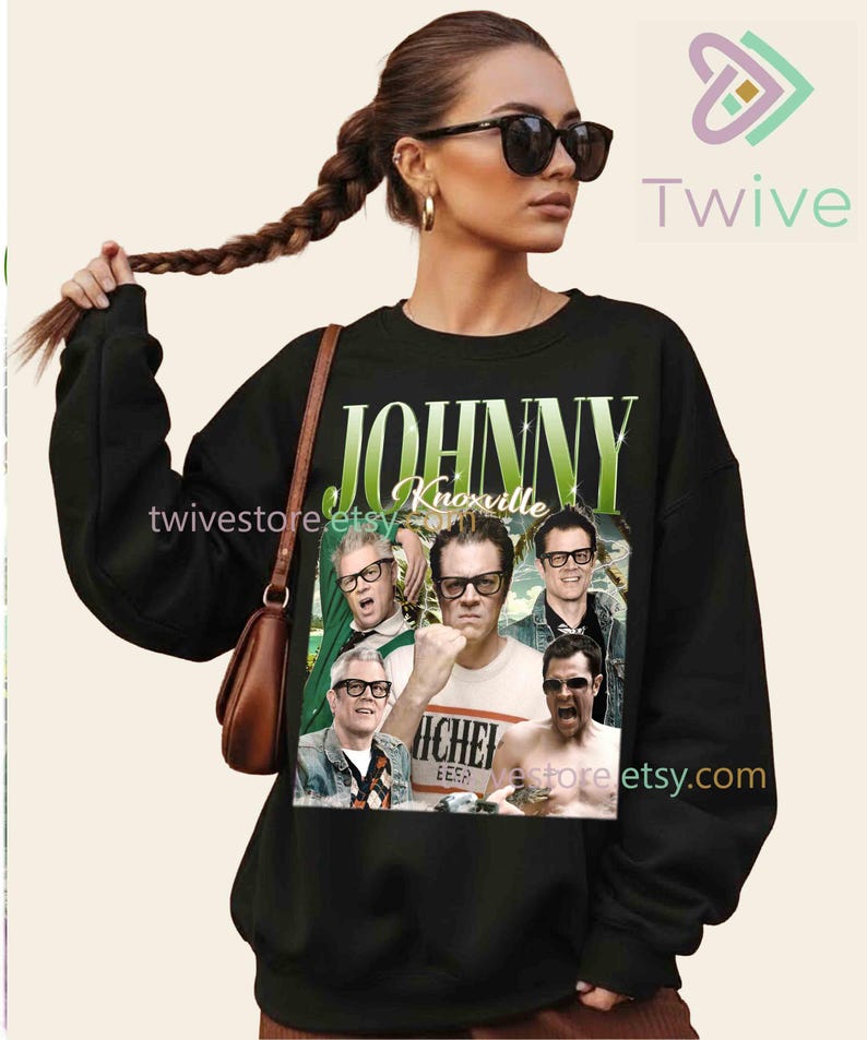 May include: Black sweatshirt featuring a collage of images of Johnny Knoxville with the text "JOHNNY Knoxville" in green and white. The sweatshirt is a crew neck style.