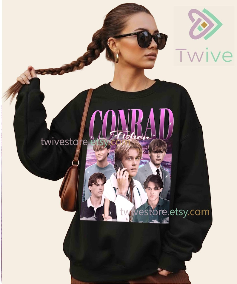 May include: Black sweatshirt featuring a graphic of the name "CONRAD Fisher" in a pink and purple gradient font, with multiple images of a person. The sweatshirt has long sleeves and a crew neck. The Etsy shop name "twivestore.etsy.com" is visible.