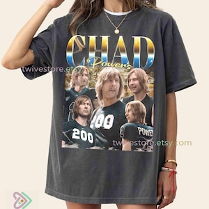 May include: Dark grey t-shirt with a graphic of a man with long blonde hair, and the text "CHAD Powers" in a gold and blue gradient. The shirt also has the text "200" and "POWERS".