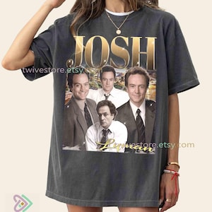 May include: Dark gray t-shirt featuring the word "JOSH" in gold lettering above a collage of four men in suits. The word "Lyman" is written in gold script below the image. The shirt has a vintage, worn look.