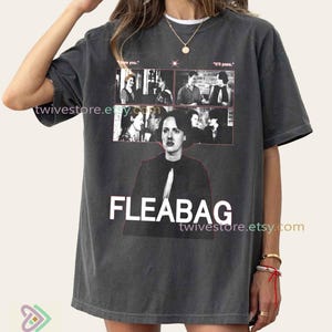 May include: Dark gray t-shirt featuring a graphic of the show "Fleabag." The design includes a collage of black and white images and the show's title in large white letters. The shirt also has the text "I love you." and "It'll pass."