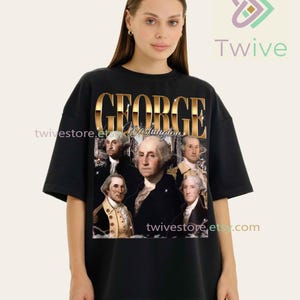 May include: Black oversized t-shirt featuring a gold-colored graphic of George Washington and the text "GEORGE Washington". The graphic includes portraits of George Washington. The shirt has short sleeves and a crew neck.