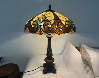 静謐な空間に漂うレトロな光と影：パッチワークのガラスランプシェードと彫刻が施された台座の間に生まれた温かみのある詩