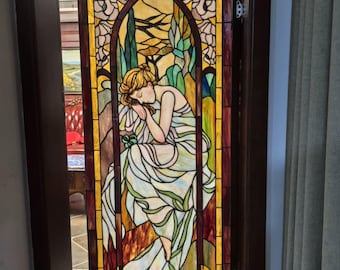 Kirchliche Glaskunst, umgeben von grünen Pflanzen und Blumen, ruhige und elegante Dekoration.