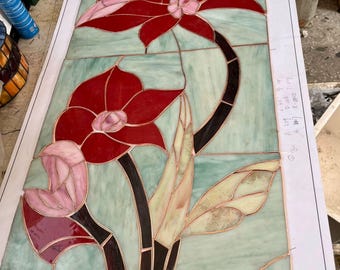 ツールボックスの前にあるステンドグラスの窓には、ピンクの花と黄色の縁取りの細部が描かれています。