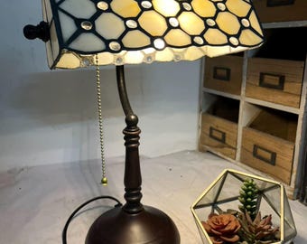 ビンテージのステンドグラス テーブル ランプの静物写真: 幾何学的な光と影の下の多肉植物と木製のフレームの背景。