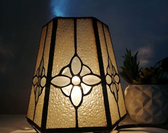 黒枠の六角形ガラステーブルランプ | 半透明の質感と白い花が飾られた居心地の良いコーナーのクローズアップ