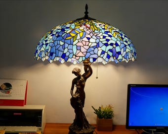 ステンドグラスのランプを持った女性像 | オフィスの隅に、青、ピンク、黄色の砕けたガラスの花びらのランプシェードが咲いています。
