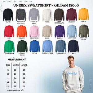 May include: A selection of Gildan 18000 unisex sweatshirts in various colors, including black, red, and navy. The image displays a size chart with measurements in inches, ranging from S to 2XL. A person is wearing a white sweatshirt with "SolyraUS" printed on it.