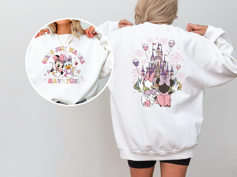 May include: White sweatshirt with a front graphic of Minnie Mouse and Daisy Duck, and the text "Girls Just Wanna Have Fun". The back features a castle design with the characters. The design includes pink, purple, and yellow accents.