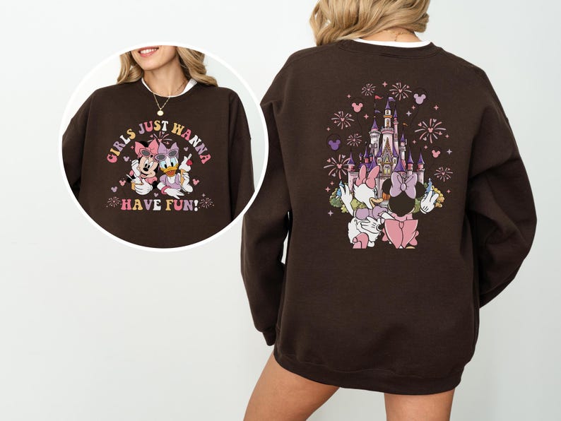 May include: A brown sweatshirt with a graphic of Minnie Mouse and Daisy Duck, and the text "GIRLS JUST WANNA HAVE FUN!" on the front. The back features a castle design with fireworks and the two characters.