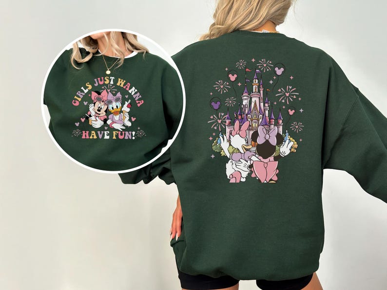 May include: Dark green sweatshirt with a cartoon design. The front features Minnie Mouse and Daisy Duck with the text "GIRLS JUST WANNA HAVE FUN!". The back shows a castle, fireworks, and more cartoon characters.