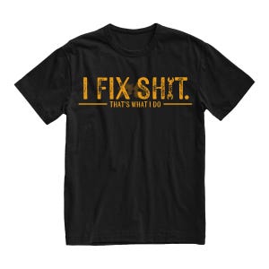 May include: Black t-shirt with the text "I FIX SHIT. THAT'S WHAT I DO" in distressed yellow lettering. The design includes a wrench and a gear icon. The shirt is a crew neck style.