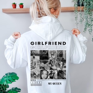 Puede incluir: Una sudadera con capucha blanca que presenta un estampado gr&aacute;fico en blanco y negro en la parte posterior. El dise&ntilde;o incluye la palabra "GIRLFRIEND" repetida tres veces, un collage de nueve fotograf&iacute;as en blanco y negro, el nombre "SONIA" y "MY QUEEN."