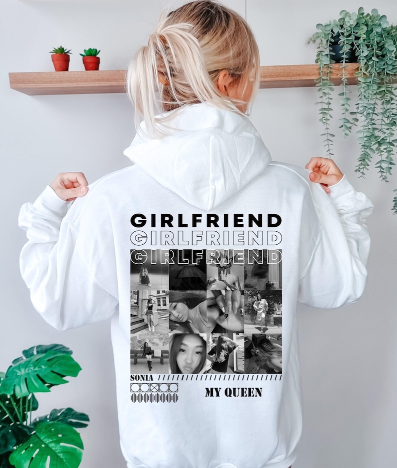 Puede incluir: Una sudadera con capucha blanca que presenta un estampado gr&aacute;fico en blanco y negro en la parte posterior. El dise&ntilde;o incluye la palabra "GIRLFRIEND" repetida tres veces, un collage de nueve fotograf&iacute;as en blanco y negro, el nombre "SONIA" y "MY QUEEN."