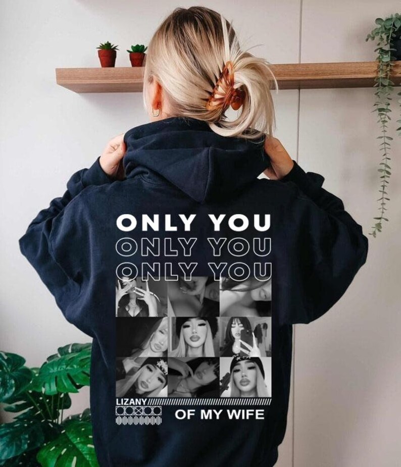 Puede incluir: Una sudadera con capucha azul marino oscuro que presenta un estampado gr&aacute;fico blanco en la espalda. El texto ONLY YOU se repite tres veces sobre una cuadr&iacute;cula de nueve fotograf&iacute;as en blanco y negro, con el texto LIZANY OF MY WIFE debajo.