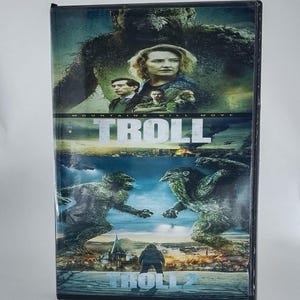 May include: A DVD case featuring the movies "Troll" and "Troll 2." The top portion shows a woman and several men, with the word "Troll" in large letters. The bottom half depicts troll-like creatures and the text "Troll 2."