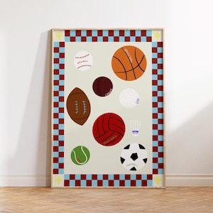 Pode incluir: Uma impressão emoldurada com várias bolas esportivas, incluindo basquete, beisebol, futebol americano, futebol, vôlei e tênis. A impressão tem um fundo creme com uma borda xadrez vermelha e azul e uma moldura de madeira.