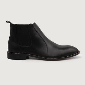 May include: A single black Chelsea boot with a rounded toe and a pull tab at the back. The boot features elastic side panels and a stitched sole. The leather boot is approximately 6 inches tall.