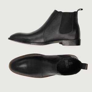 May include: Black leather Chelsea boots. The boots have a rounded toe, elastic side panels, and a pull tab at the back. The sole is a dark color. The boots are shown from the side and from above.