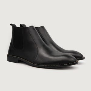 May include: A pair of black leather Chelsea boots. The boots have a rounded toe, elastic side panels, and a pull tab at the back. The soles are stitched with a light-colored thread. The boots are displayed on a white background.