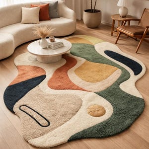 Könnte beinhalten: Abstrakter Teppich mit einer einzigartigen, organischen Form. Der Teppich hat eine cremefarbene Basis mit großen, unregelmäßigen Formen in Orange, Gelb, Grün und Marineblau. Ein strukturiertes, getuftetes Design verleiht dieser modernen Wohnkultur einen besonderen Reiz.