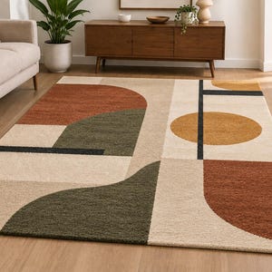 May include: A rectangular area rug featuring a geometric pattern with large shapes in terracotta, olive green, and mustard yellow on a cream-colored background. The design includes bold black lines and curved forms arranged in a balanced composition.