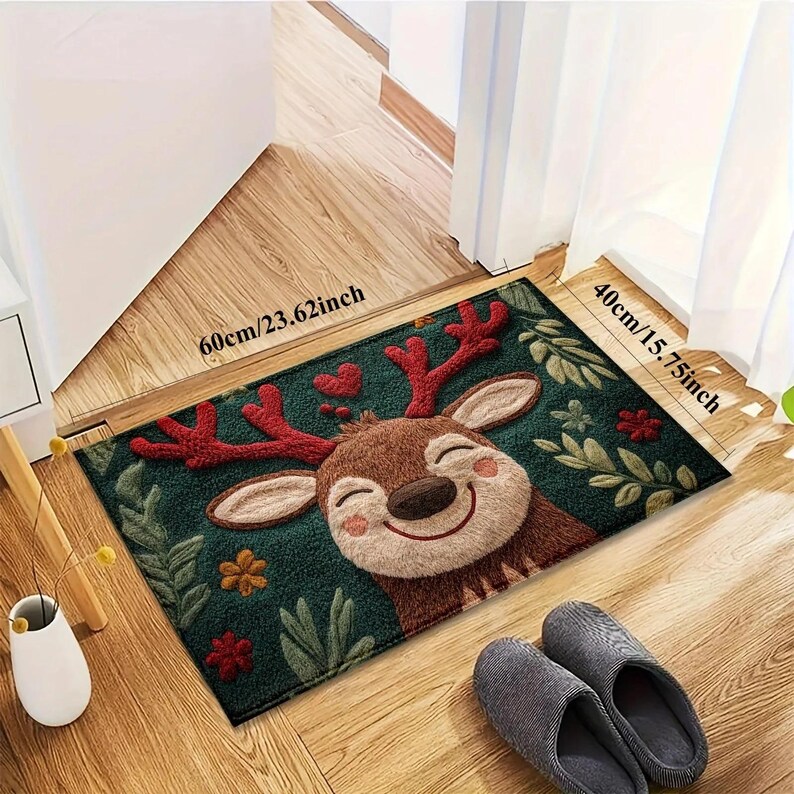 May include: A rectangular doormat featuring a smiling cartoon reindeer with red antlers and a green background. The mat measures 23.62 inches by 15.75 inches and is decorated with hearts and floral accents. A pair of gray slippers rests nearby.