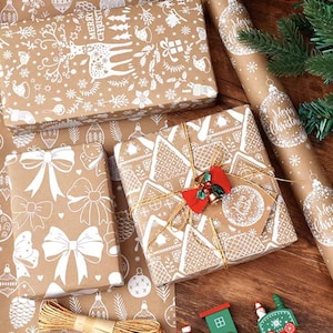 Könnte beinhalten: Weihnachtliches Geschenkpapier. Geschenke verpackt in braunem Papier mit weißen festlichen Mustern, darunter Schleifen, Ornamente und Rentiere. Passendes Geschenkpapier und Bindfaden sind ebenfalls zu sehen. Ein Geschenk ist mit einer roten Schleife und einem Anhänger verziert.