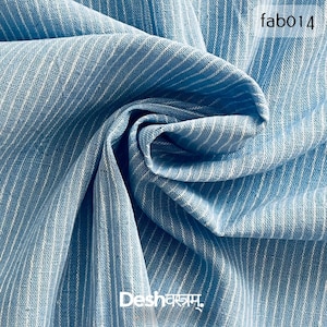 Può includere: Primo piano di un tessuto azzurro con strisce verticali bianche. Il tessuto è piegato, mostrando la sua consistenza. Il testo "fab014" è nell'angolo in alto a destra. Il testo "Deshakam" è nell'angolo in basso a sinistra.