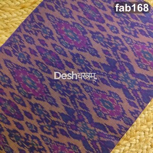 May include: A piece of fabric featuring a repeating purple, blue, and dark violet ikat-style pattern. The text "fab168" appears in the top right corner, and the text "Deshवस्त्रम्" is printed in white in the center of the fabric.