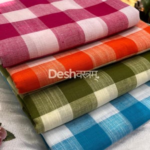 May include: A stack of four folded fabric pieces featuring a checkered pattern in magenta, orange, olive green, and blue, each paired with white. The text fab139 and Deshवस्त्रम् are visible on the fabric. The material has a visible woven texture.