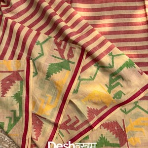 May include: Cream-colored fabric with red stripes and a decorative border. The border features a repeating pattern in red, green, and yellow. The text "Fab096" is in the upper right corner, and the text "Deshवस्त्रम" is near the bottom.