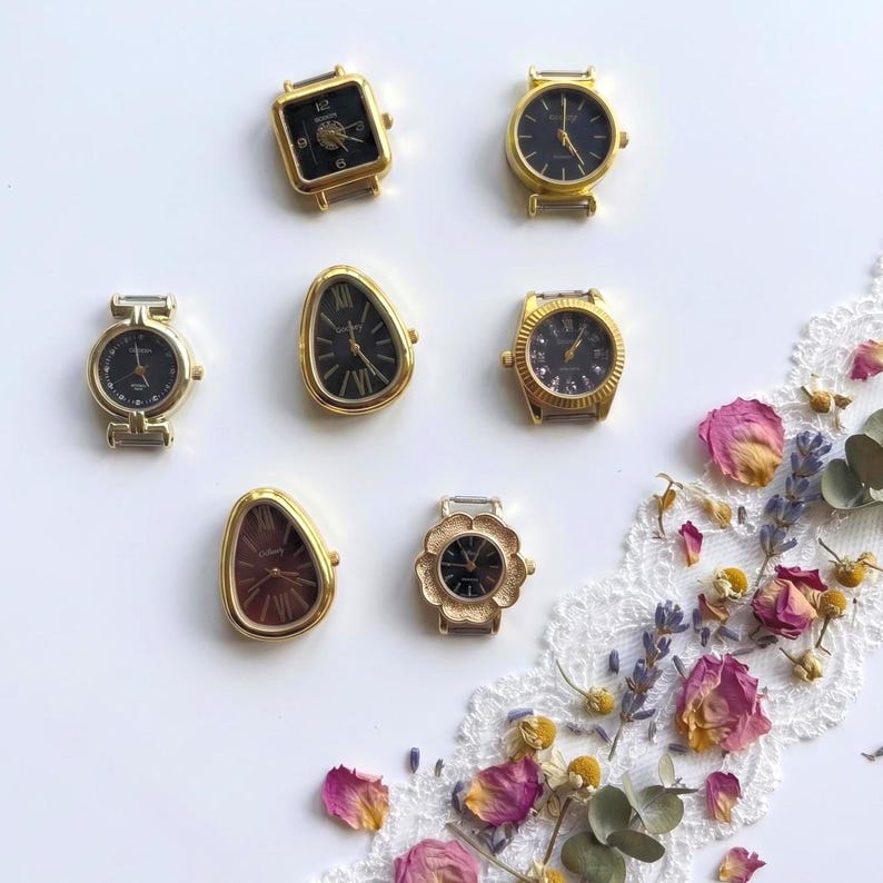 May include: Seven gold-tone watch faces with black dials, featuring various shapes including square, round, teardrop, and floral designs. Each watch face displays hour and minute hands, with some showing Roman or Arabic numerals on the dial.