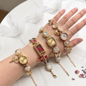 May include: A collection of gold-toned bracelet watches with various decorative elements. Each watch features a different face shape and is adorned with pearls, crystals, and butterfly charms. The watch faces display the time.