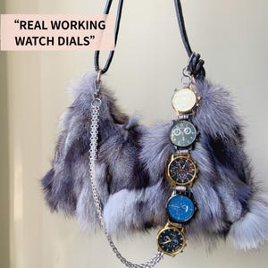 May include: A gray fur handbag with a black leather strap and a silver chain. The bag is adorned with five working watch dials in various colors, including gold, black, and blue. The text "REAL WORKING WATCH DIALS" is in the upper left corner.