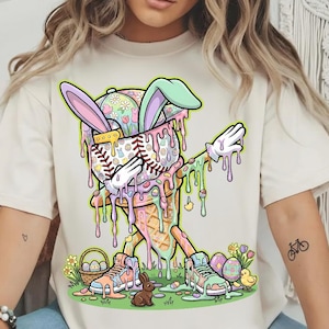 May include: Cream-colored t-shirt featuring a colorful Easter-themed graphic. The design includes a baseball-shaped ice cream cone with bunny ears, dripping with pastel colors, and a pair of sneakers with Easter eggs and a bunny. The graphic is whimsical and festive.